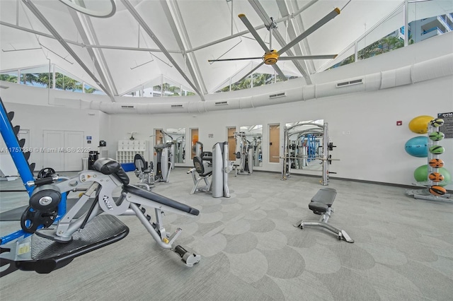 exercise room with high vaulted ceiling, baseboards, and visible vents