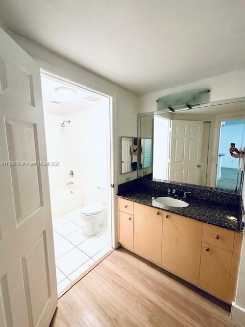 bathroom featuring toilet, shower / bathing tub combination, wood finished floors, and vanity