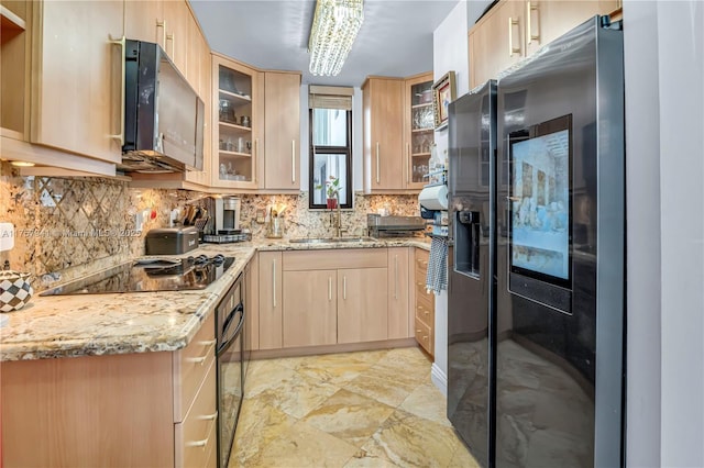 kitchen with light stone counters, light brown cabinets, a sink, black appliances, and tasteful backsplash