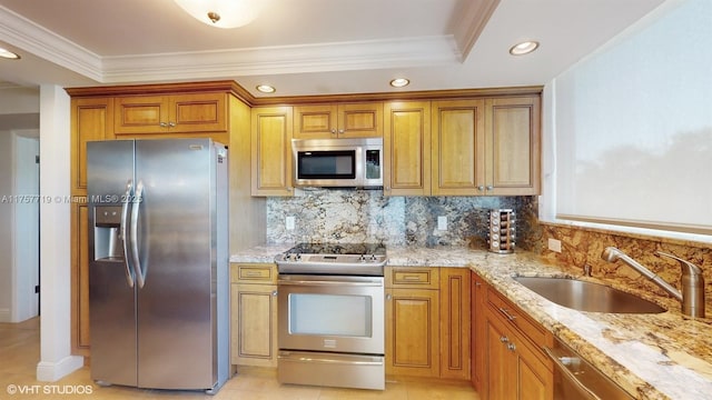 kitchen featuring light stone countertops, a sink, appliances with stainless steel finishes, backsplash, and brown cabinets