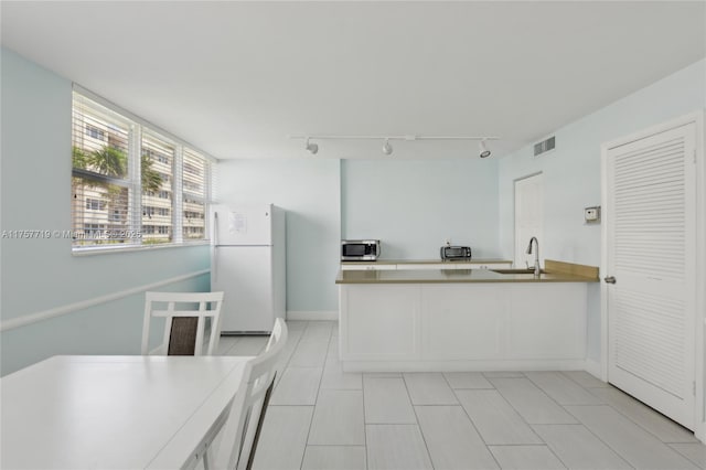 1236 Hillsboro Mile Unit 403, Hillsboro Beach, FL 33062 - kitchen featuring a sink, light tile patterned flooring, stainless steel microwave, visible vents, and freestanding refrigerator
