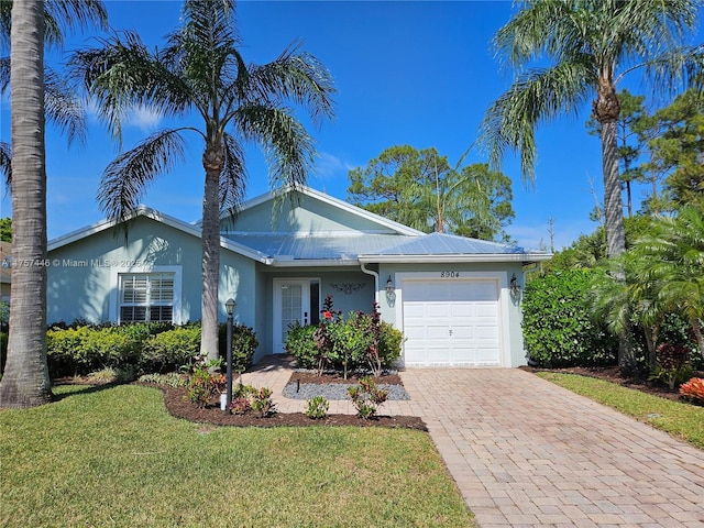 ranch-style home with stucco siding, an attached garage, decorative driveway, and a front yard