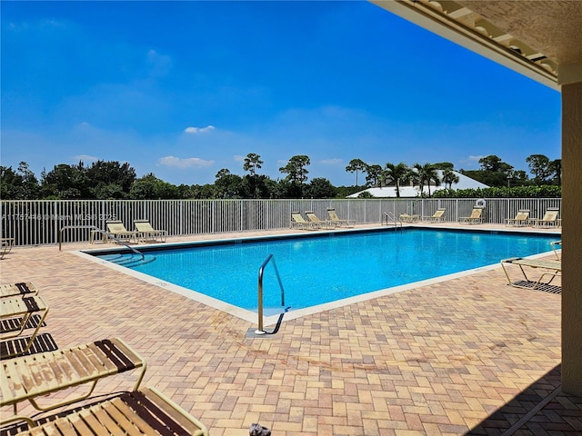 community pool with a patio area and fence