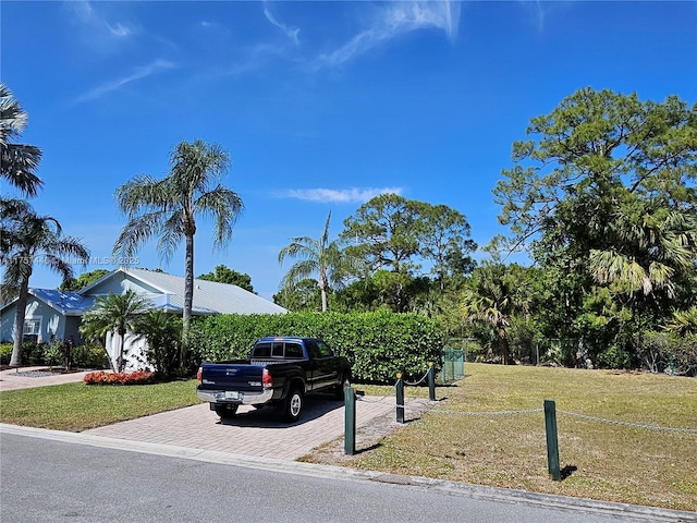 view of front of property featuring a front yard, decorative driveway, and metal roof