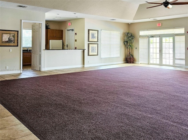 unfurnished living room with carpet floors, baseboards, visible vents, and tile patterned floors