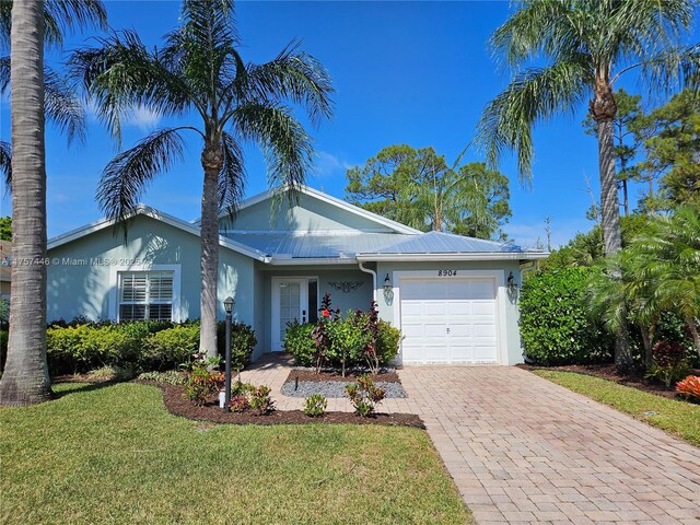 8904 SW Fishermans Wharf Dr, Stuart, FL 34997 - ranch-style house with an attached garage, decorative driveway, stucco siding, and a front yard
