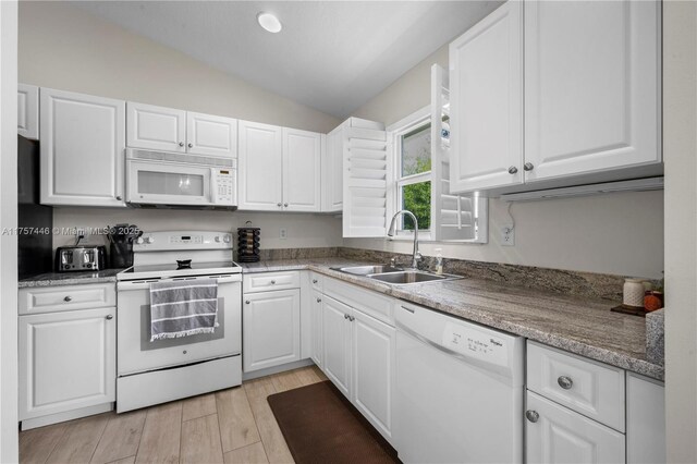 8904 SW Fishermans Wharf Dr, Stuart, FL 34997 - kitchen with white appliances, a sink, vaulted ceiling, white cabinets, and light wood finished floors
