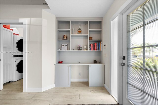 8904 SW Fishermans Wharf Dr, Stuart, FL 34997 - laundry room with stacked washer / dryer, light wood-style flooring, a desk, and baseboards