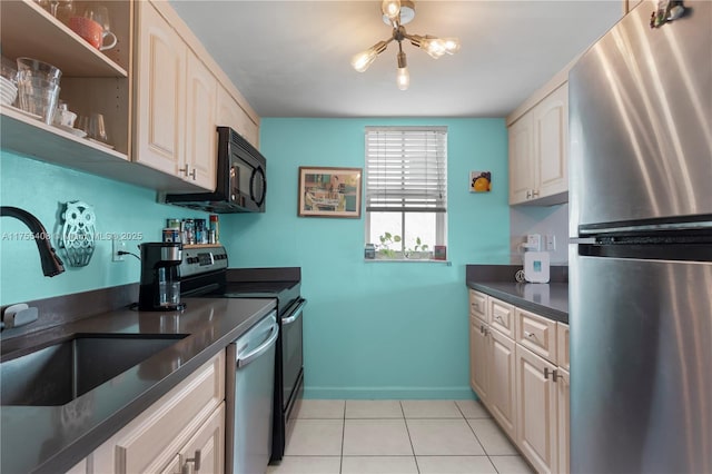 kitchen featuring light tile patterned floors, stainless steel appliances, a sink, baseboards, and dark countertops