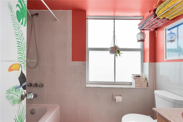 bathroom featuring toilet, vanity, tile walls, wainscoting, and shower / bath combo