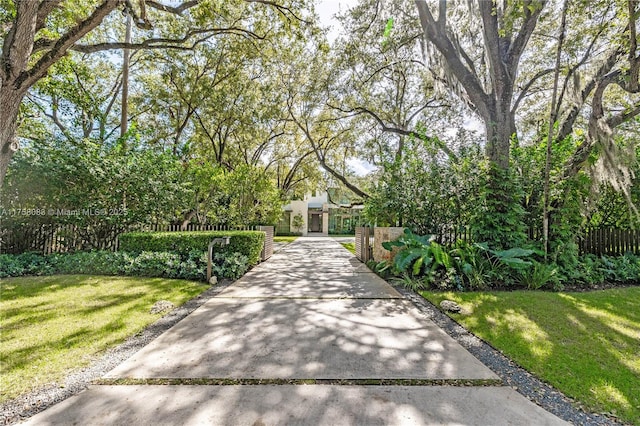 view of property hidden behind natural elements featuring a front yard and fence