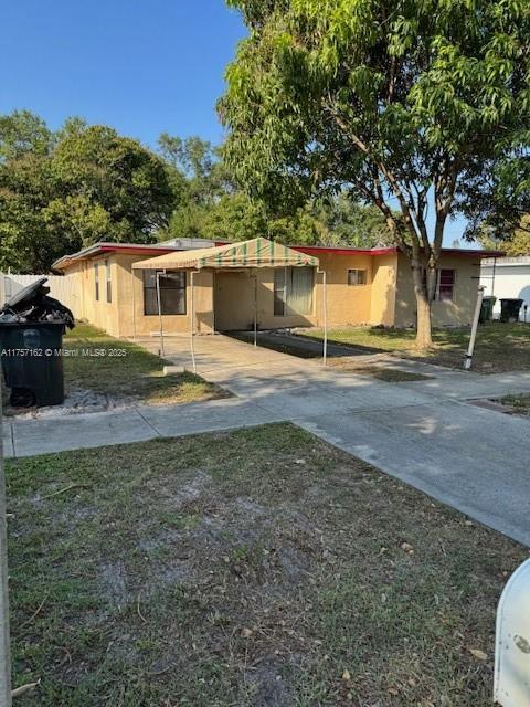 view of front of house with a carport, fence, and driveway