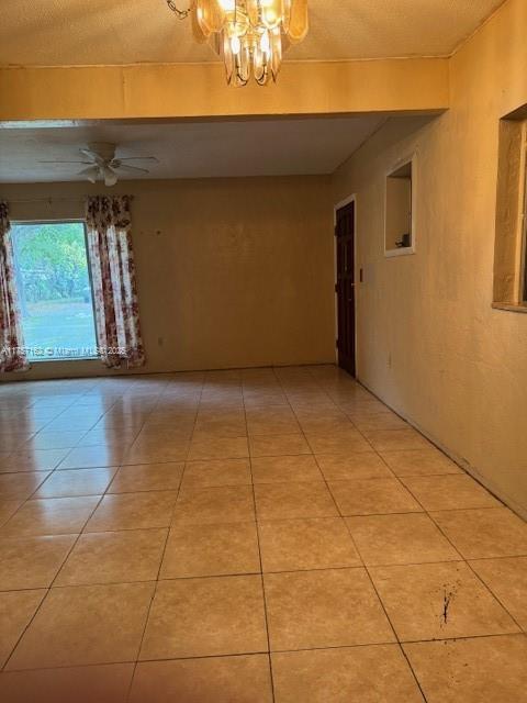 spare room with light tile patterned floors and ceiling fan with notable chandelier