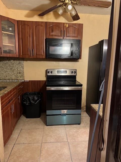 kitchen with light tile patterned floors, decorative backsplash, a ceiling fan, glass insert cabinets, and black appliances