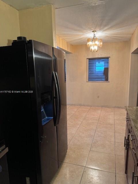 kitchen featuring light tile patterned floors, a chandelier, and black fridge