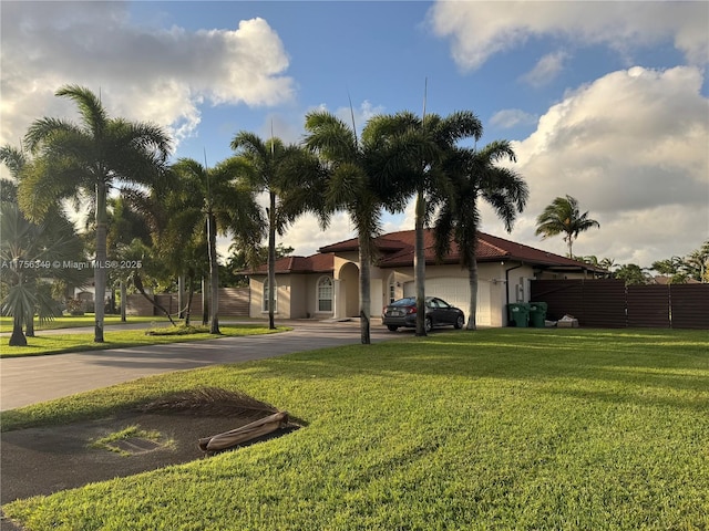 view of front of property with a garage, driveway, fence, a front lawn, and stucco siding