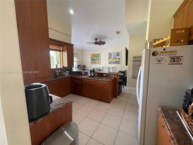 kitchen with light tile patterned floors, visible vents, a peninsula, freestanding refrigerator, and ceiling fan