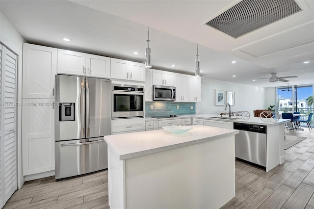 kitchen featuring visible vents, decorative backsplash, a peninsula, stainless steel appliances, and a sink