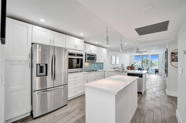 kitchen featuring a center island, decorative backsplash, appliances with stainless steel finishes, a sink, and a peninsula