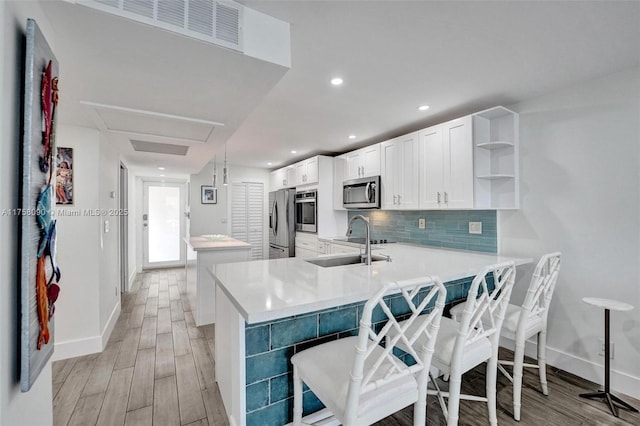 kitchen with a sink, appliances with stainless steel finishes, a center island, open shelves, and tasteful backsplash