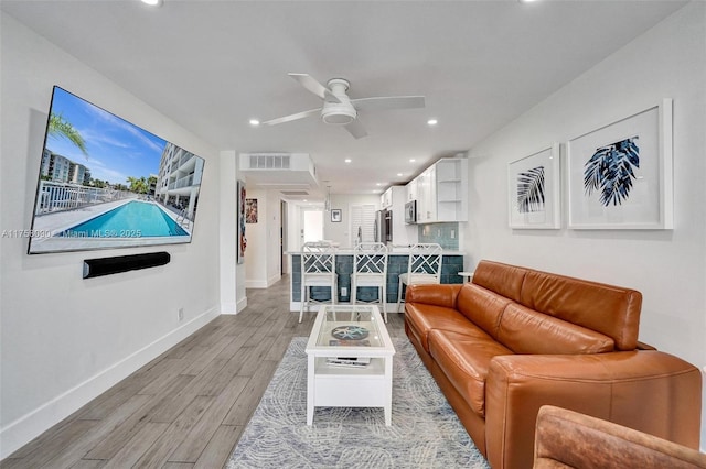 living room featuring visible vents, baseboards, a ceiling fan, light wood-type flooring, and recessed lighting