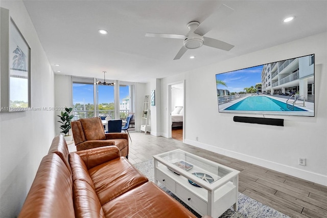 living area featuring baseboards, ceiling fan with notable chandelier, wood finished floors, and recessed lighting