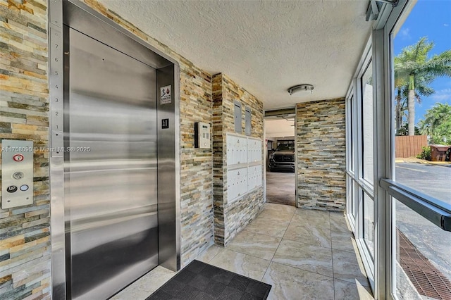 interior space with a textured ceiling, mail area, and elevator