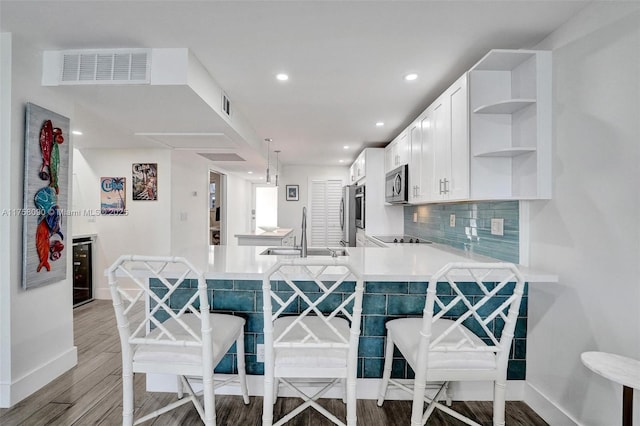 kitchen with a sink, light wood-style floors, fridge, open shelves, and stainless steel microwave