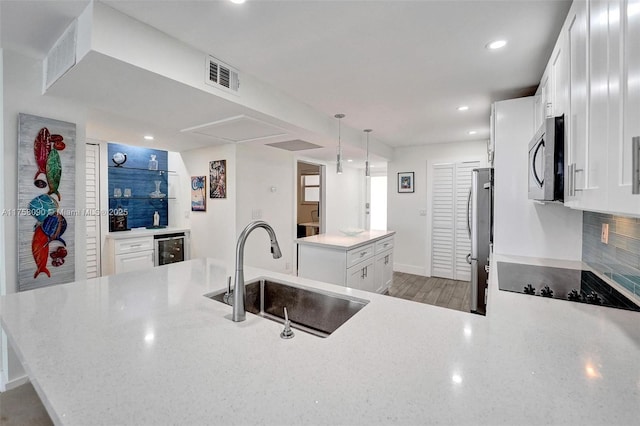 kitchen with a sink, visible vents, a center island, appliances with stainless steel finishes, and decorative backsplash