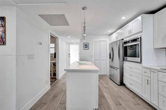 kitchen featuring appliances with stainless steel finishes, a center island, wood finish floors, and white cabinetry