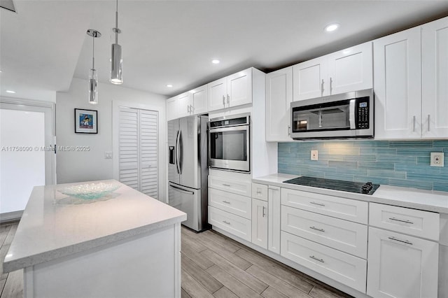 kitchen with white cabinets, appliances with stainless steel finishes, backsplash, wood tiled floor, and decorative light fixtures