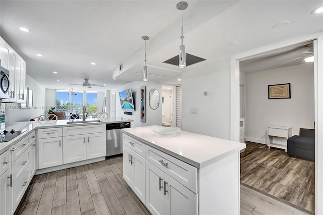 kitchen featuring a peninsula, stainless steel appliances, a sink, and wood finish floors