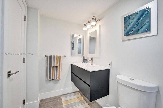 bathroom with vanity, wood finished floors, toilet, and baseboards