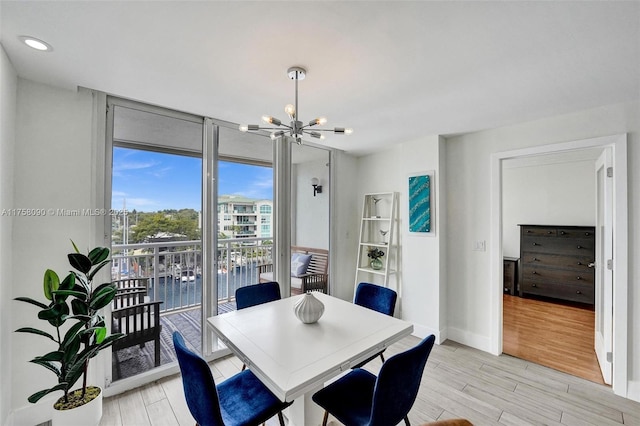 dining space with light wood-style flooring, floor to ceiling windows, a chandelier, and baseboards