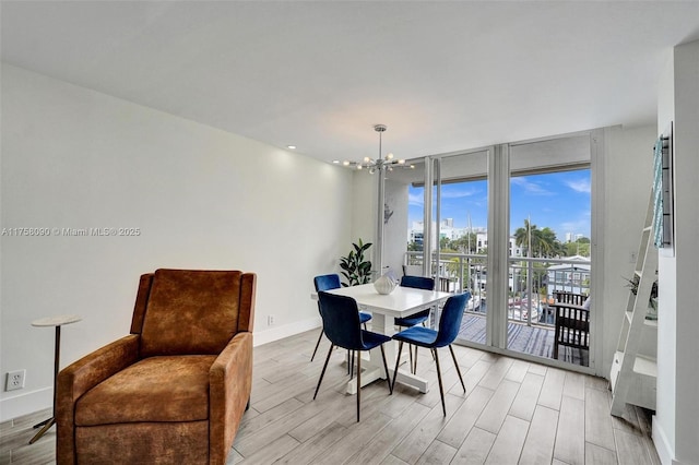 dining area featuring light wood finished floors, baseboards, a wall of windows, and a chandelier