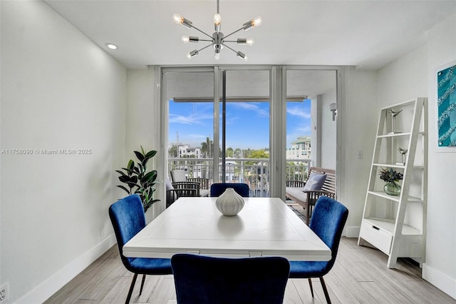 dining room with a chandelier, a wall of windows, light wood-type flooring, and baseboards