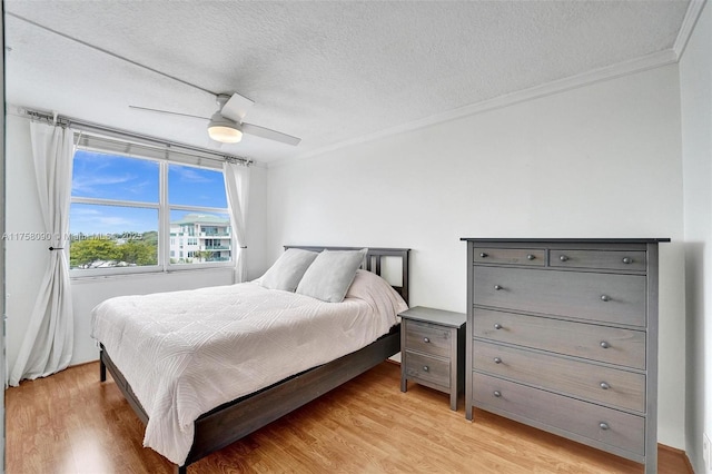 bedroom with light wood finished floors, a ceiling fan, ornamental molding, and a textured ceiling