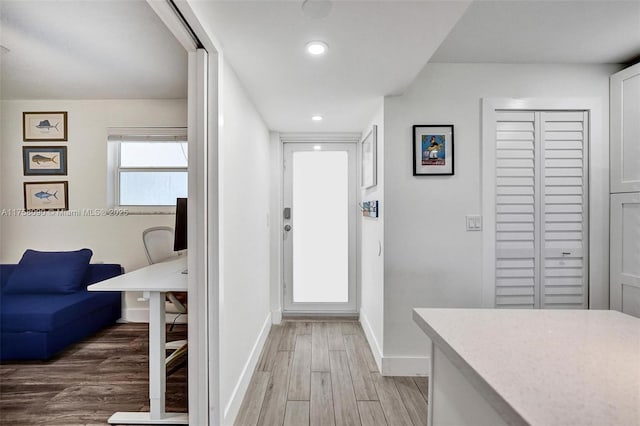 interior space featuring recessed lighting, baseboards, and light wood finished floors