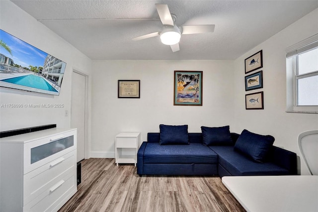 living room featuring ceiling fan, a textured ceiling, and wood finished floors