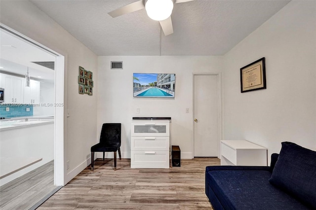 sitting room with visible vents, ceiling fan, a textured ceiling, and light wood finished floors