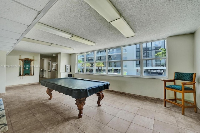 recreation room featuring baseboards, a textured ceiling, and tile patterned floors