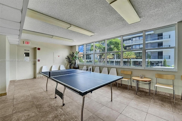 game room featuring a textured ceiling, tile patterned flooring, and baseboards