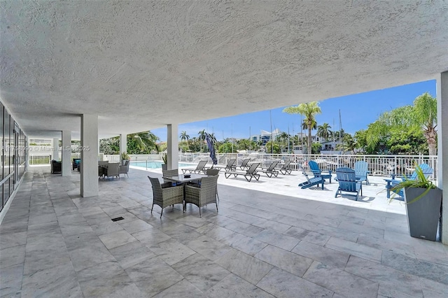 view of patio featuring a community pool and fence