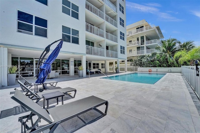 pool with a patio area and fence