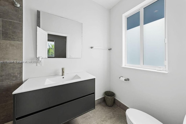 bathroom with tile patterned flooring, vanity, toilet, and baseboards