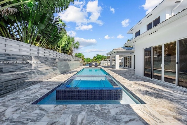 pool with a patio, fence, and an in ground hot tub