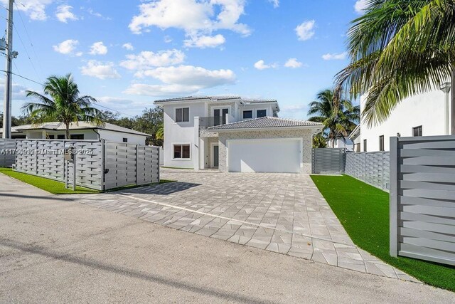 view of front of house featuring a fenced front yard, a garage, a tile roof, decorative driveway, and stucco siding