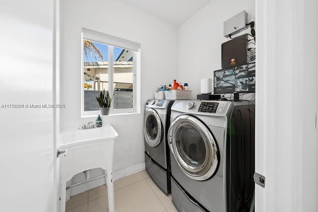 laundry room featuring washing machine and clothes dryer, light tile patterned flooring, a sink, laundry area, and baseboards