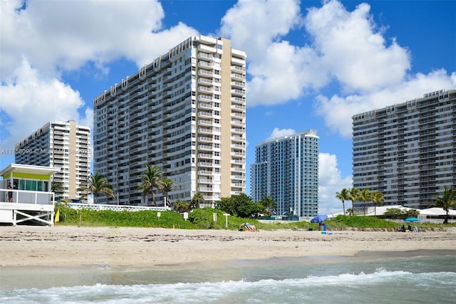 view of building exterior featuring a water view and a beach view