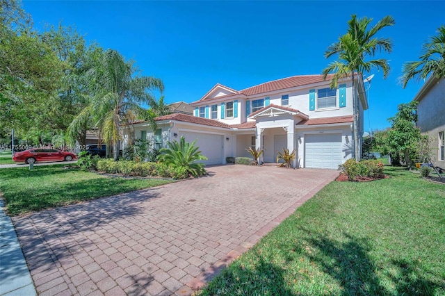 mediterranean / spanish-style home with a tiled roof, a front lawn, decorative driveway, and stucco siding